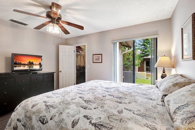 bedroom featuring a textured ceiling, ceiling fan, visible vents, access to outside, and a walk in closet