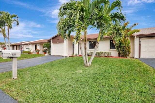 ranch-style home featuring a garage, driveway, and a front lawn