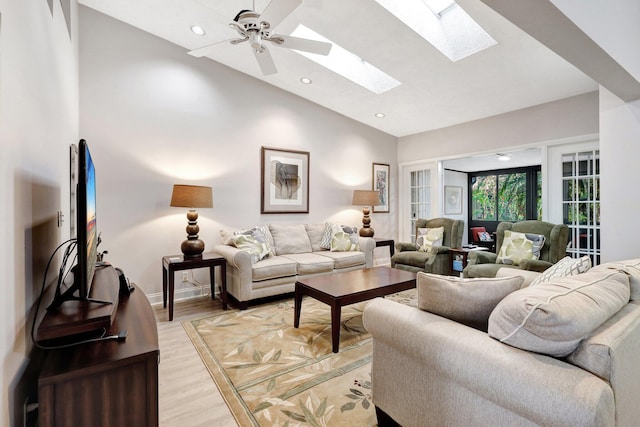 living room with a skylight, light wood finished floors, recessed lighting, high vaulted ceiling, and baseboards