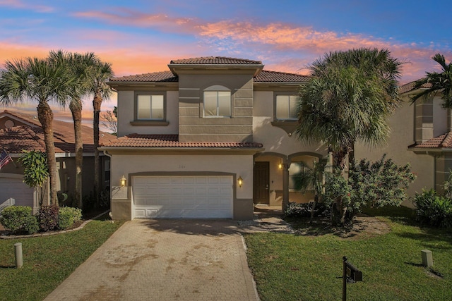 mediterranean / spanish-style house featuring a tiled roof, decorative driveway, a front yard, and stucco siding