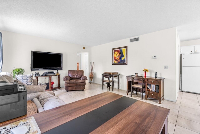 living room featuring light tile patterned floors, a textured ceiling, visible vents, and baseboards