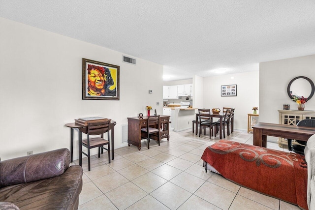 living room featuring light tile patterned floors, a textured ceiling, and visible vents