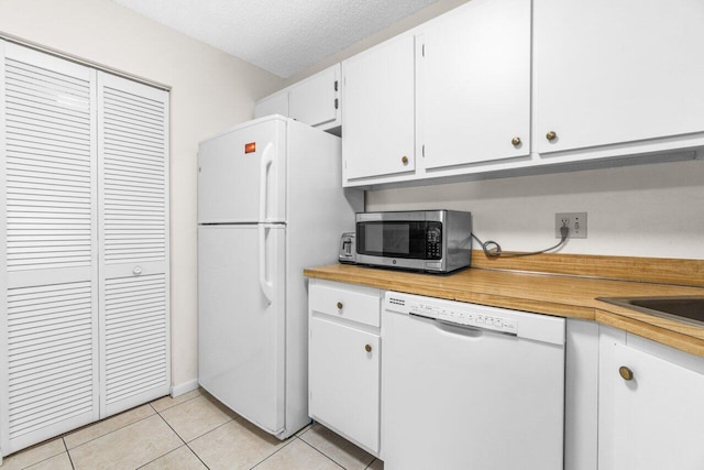 kitchen with light tile patterned floors, white appliances, light countertops, and white cabinets