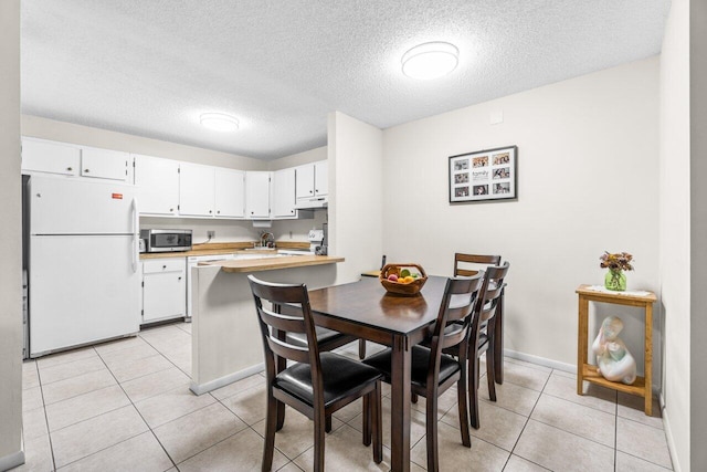 dining room featuring light tile patterned flooring, a textured ceiling, and baseboards