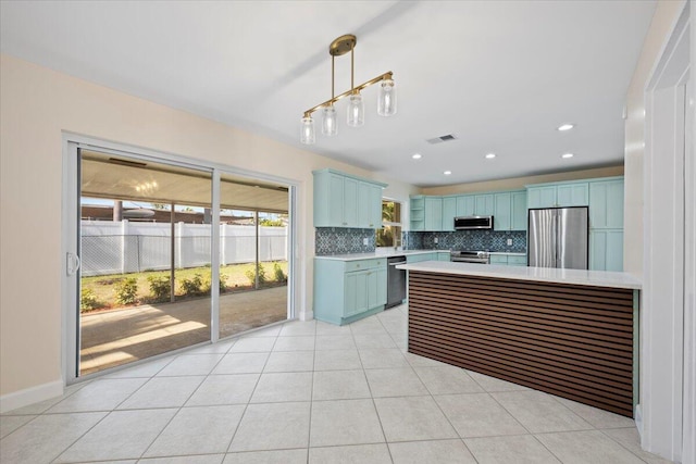 514 Jaeger Dr, Delray Beach, FL 33444 - kitchen with appliances with stainless steel finishes, blue cabinets, light countertops, decorative backsplash, and hanging light fixtures