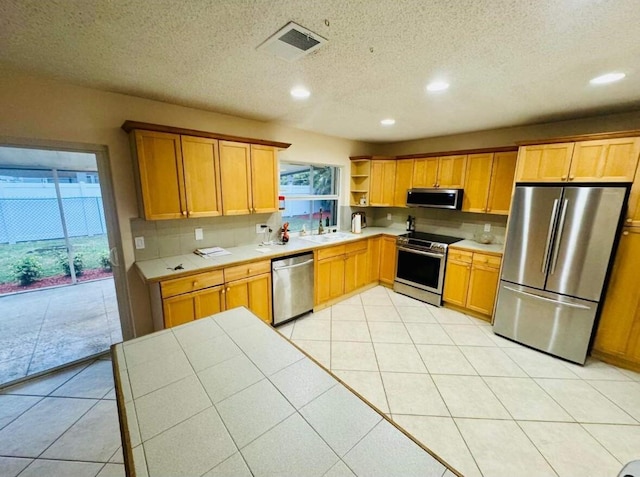 kitchen featuring light tile patterned floors, visible vents, decorative backsplash, appliances with stainless steel finishes, and a sink