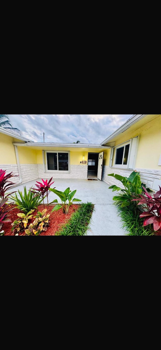 view of exterior entry with a patio and stucco siding