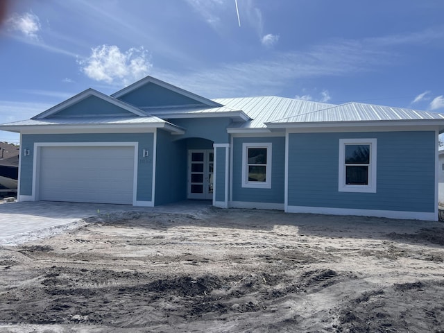 ranch-style house with a garage, decorative driveway, and metal roof