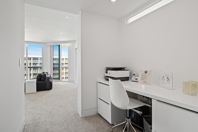 home office featuring baseboards, floor to ceiling windows, built in desk, and light colored carpet