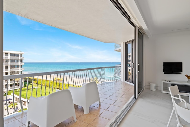 balcony with a water view and a view of the beach