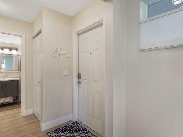 entryway with light wood-type flooring, baseboards, and a sink