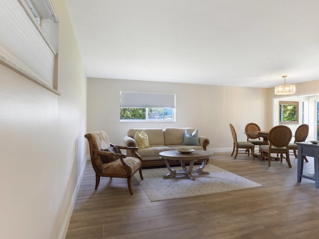 living area with baseboards, wood finished floors, and a chandelier