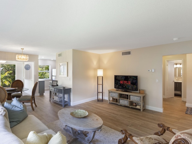 living area featuring visible vents, baseboards, wood finished floors, and a chandelier