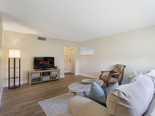 living area featuring baseboards, wood finished floors, and visible vents