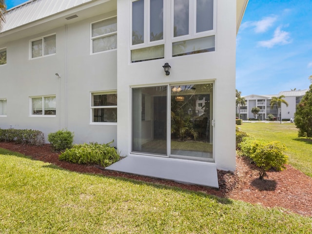 rear view of property with a lawn and stucco siding