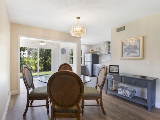 dining area with baseboards, wood finished floors, visible vents, and ceiling fan with notable chandelier