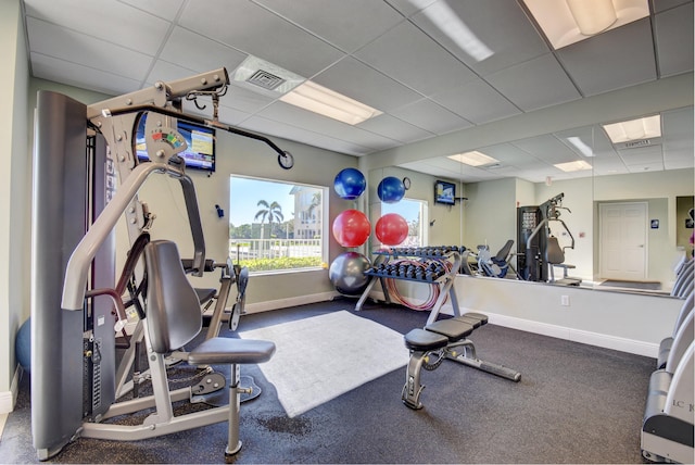 exercise room with baseboards, visible vents, and a paneled ceiling
