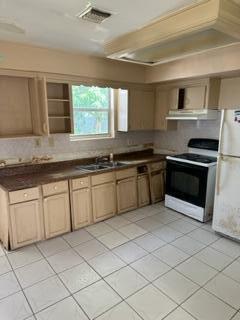 kitchen with light tile patterned floors, dark countertops, visible vents, a sink, and white appliances