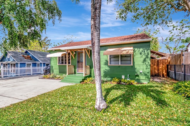 bungalow-style home with fence and a front yard