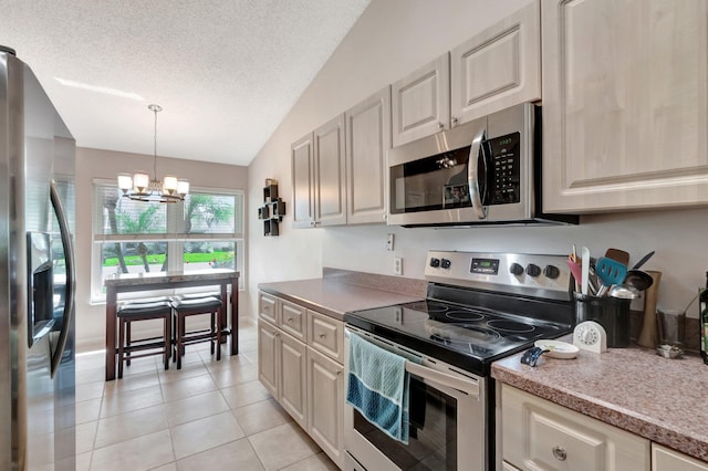 kitchen featuring decorative light fixtures, a notable chandelier, light tile patterned floors, stainless steel appliances, and a textured ceiling