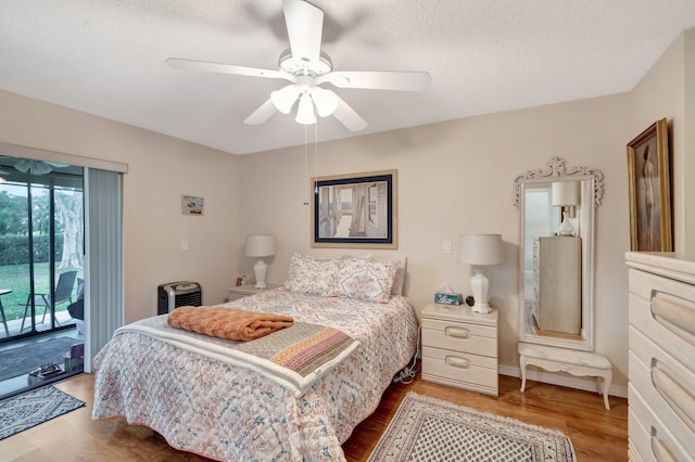 bedroom featuring access to exterior, a ceiling fan, a textured ceiling, wood finished floors, and baseboards