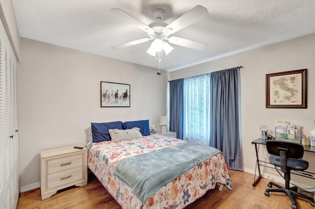 bedroom with light wood-type flooring, a closet, a textured ceiling, and baseboards