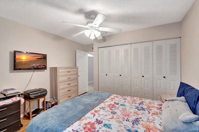 bedroom featuring a textured ceiling, light wood finished floors, a closet, and a ceiling fan