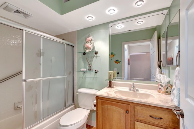 bathroom featuring toilet, shower / bath combination with glass door, vanity, and visible vents