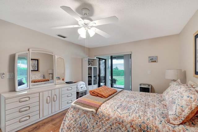 bedroom featuring a textured ceiling, light wood finished floors, visible vents, and access to exterior