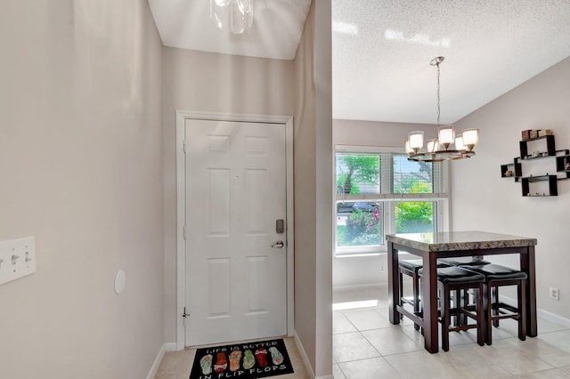 entryway with baseboards, vaulted ceiling, a textured ceiling, a chandelier, and light tile patterned flooring