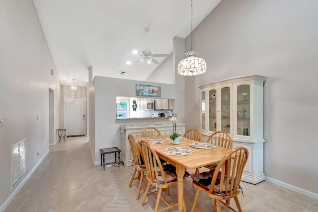 dining room featuring high vaulted ceiling, visible vents, baseboards, and light tile patterned floors