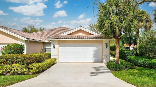 view of front of house featuring a tiled roof, an attached garage, driveway, and stucco siding