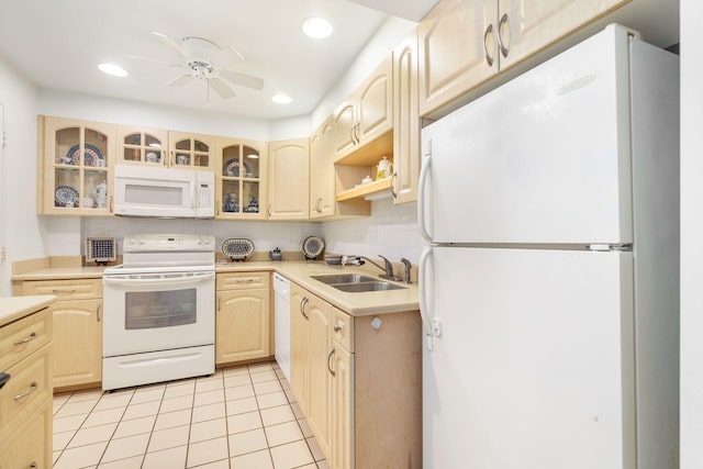 kitchen featuring white appliances, glass insert cabinets, light countertops, light brown cabinetry, and a sink