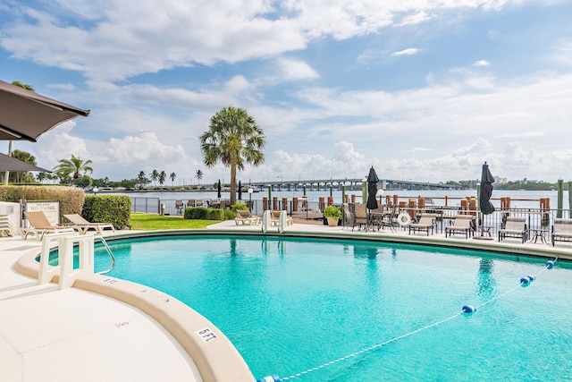 pool featuring a patio area, a water view, and fence