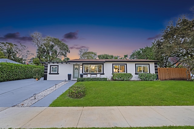 ranch-style home featuring a yard, fence, and stucco siding