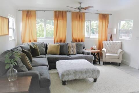 living room featuring ceiling fan, a wealth of natural light, and light colored carpet