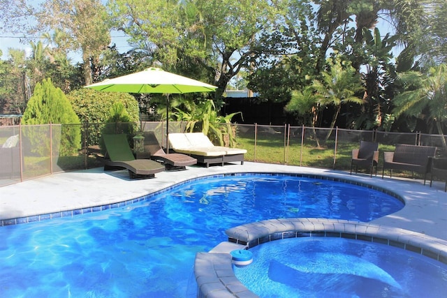 view of pool with a patio area, a pool with connected hot tub, and fence