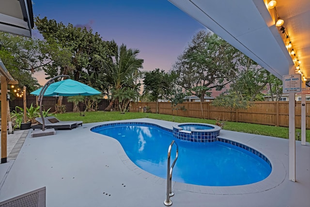 pool at dusk featuring a pool with connected hot tub, a fenced backyard, a lawn, and a patio