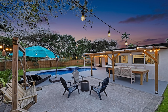 view of swimming pool with a patio, a pool with connected hot tub, area for grilling, fence, and a fire pit