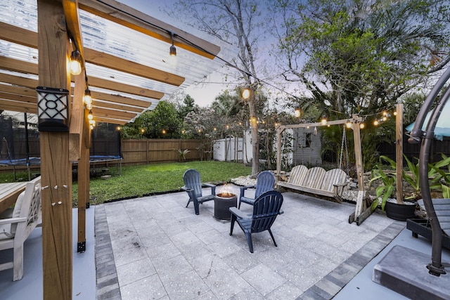 view of patio with an outdoor fire pit, a trampoline, and a fenced backyard