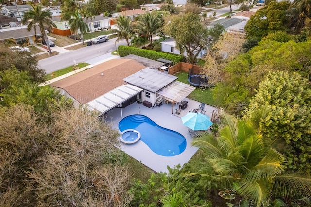 view of pool with a fenced backyard, a trampoline, a pool with connected hot tub, and a patio