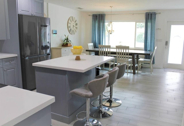 kitchen featuring a kitchen island, a breakfast bar, light countertops, and freestanding refrigerator