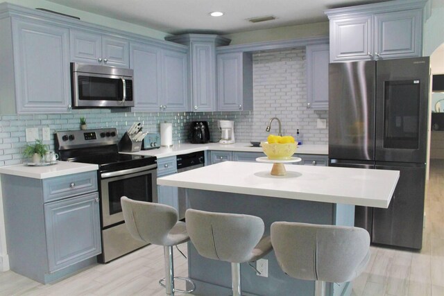 kitchen featuring a sink, visible vents, appliances with stainless steel finishes, decorative backsplash, and a kitchen bar