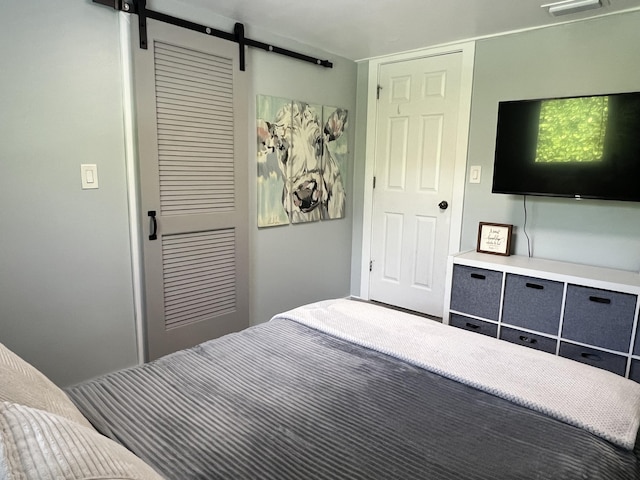 bedroom with a barn door, a closet, and visible vents