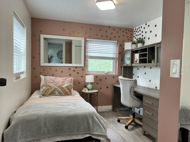 bedroom with light wood-type flooring, wallpapered walls, and baseboards