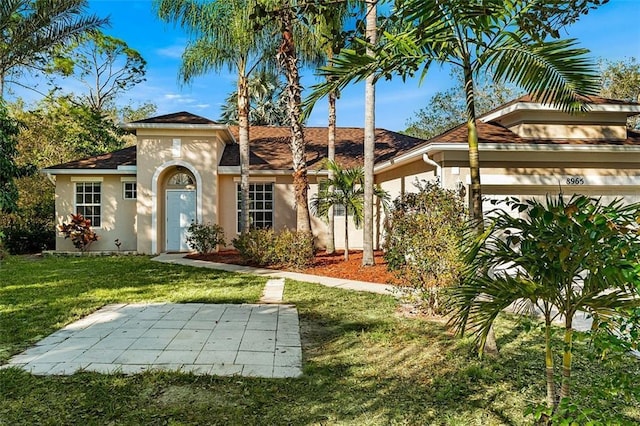 view of front of home featuring a front yard, an attached garage, and stucco siding