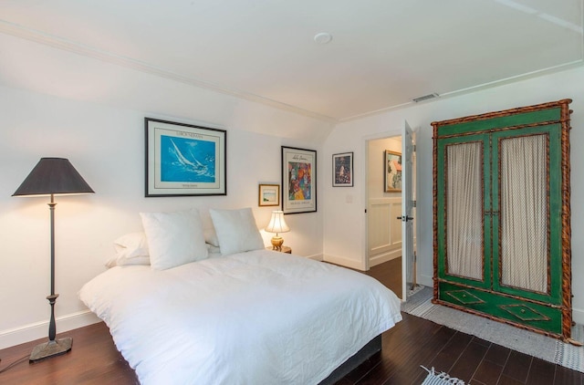 bedroom with dark wood-style flooring, visible vents, vaulted ceiling, and baseboards