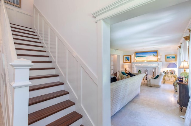 stairway with ornamental molding, wainscoting, and a decorative wall