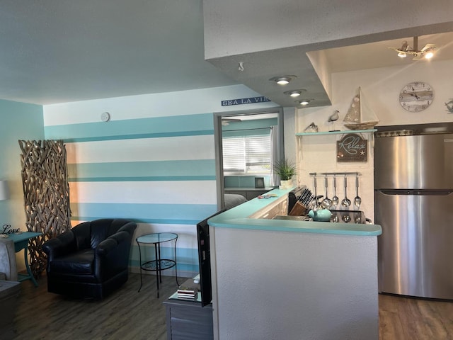 kitchen featuring a peninsula, dark wood finished floors, and freestanding refrigerator