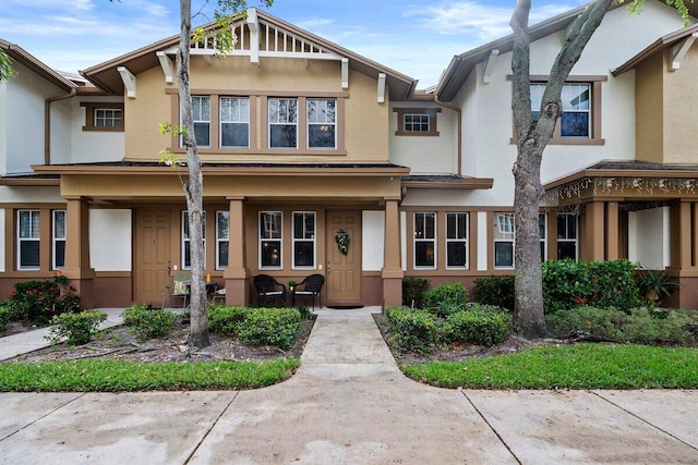 townhome / multi-family property featuring covered porch and stucco siding